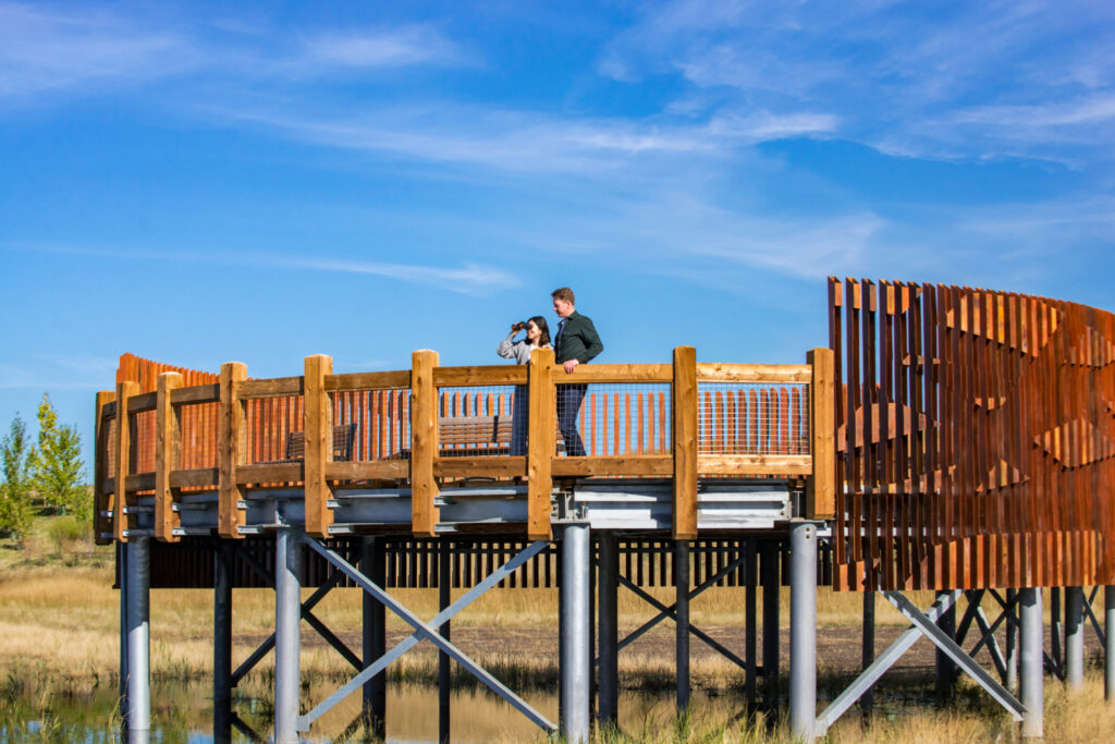 A man and a woman standing on the Hotchkiss boardwalk and bird blind structure